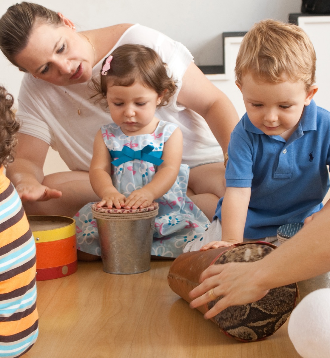 Bebê e família tocando tambores numa aula de musicalização